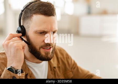 Jeune homme résolution de problèmes techniques dans un centre d'appels pendant une journée de travail chargée Banque D'Images