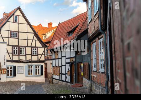 La rue pavée étroite avec des maisons à pans de bois brille par la lumière du jour chaude. Scène de Quedlinburg capture le charme médiéval, les toits colorés, et Banque D'Images