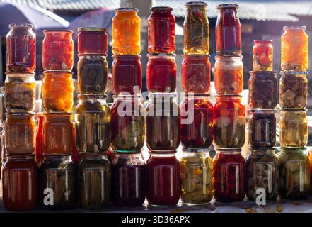 Rangée de bocaux en verre coloré remplis de légumes marinés et de conserves pour l'affichage au marché Banque D'Images