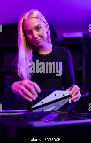 Jeune femme caucasienne améliore le PC de jeu dans une configuration éclairée au néon, mettant en valeur la concentration et les compétences technologiques Banque D'Images