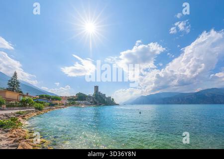 Vue sur le château historique de Scaliger perché sur la rive rocheuse du lac de Garde à Malcesine, Italie. Un soleil d'été éclatant et une eau bleue claire créent un ID Banque D'Images