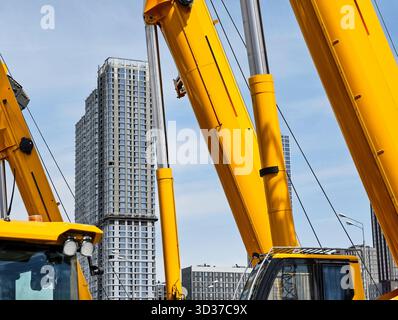 Les grues de construction dominent un horizon urbain moderne avec plusieurs bâtiments en arrière-plan sur un ciel bleu clair Banque D'Images