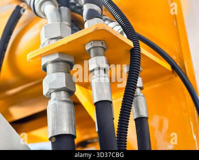 Vue rapprochée des connexions hydrauliques sur les équipements de construction présentant les composants de machines détaillés et les aspects de maintenance Banque D'Images