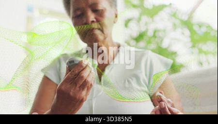 Vérification de la femme senior inspectant la glycémie dans le salon, avec lecteur de glucose et bandelette de test Banque D'Images