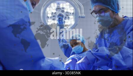 Équipe d'opération soulevant la lumière chirurgicale et ajustant les instruments dans la salle d'opération, avec moniteurs Banque D'Images