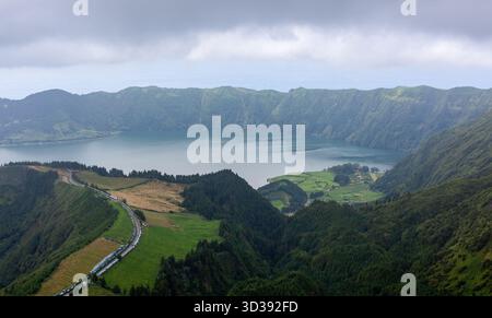 Vue panoramique sur le lac de caldeira Sete Cidades à Sao Miguel, Açores, Portugal, avec une végétation luxuriante et route sinueuse. Banque D'Images