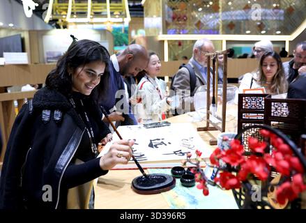 Londres, Grande-Bretagne. 4 novembre 2025. Une femme fait l'expérience de la calligraphie chinoise au pavillon chinois du World Travel Market (WTM) Londres 2025 à Londres, Grande-Bretagne, 4 novembre 2025. Le WTM London 2025 a ouvert ses portes mardi, le pavillon de la Chine attirant l’attention pour ses ressources touristiques abondantes et son attrait culturel. Crédit : Li Ying/Xinhua/Alamy Live News Banque D'Images