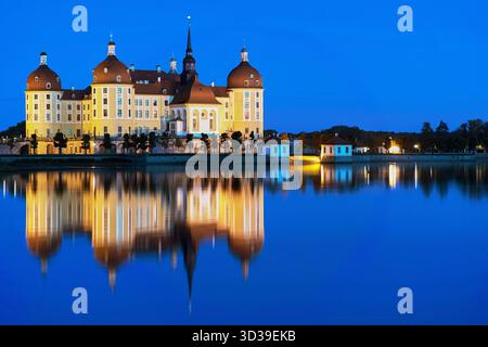 Château de Moritzburg illuminé reflété dans le lac calme au crépuscule, pavillon de chasse baroque avec reflet symétrique parfait, Saxe, Allemagne Banque D'Images