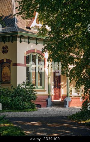 Usquert, pays-Bas ; 11 juin 2023 : charmante villa historique avec boiseries ornées, fenêtres cintrées et façade en briques détaillée partiellement cachée derrière lus Banque D'Images
