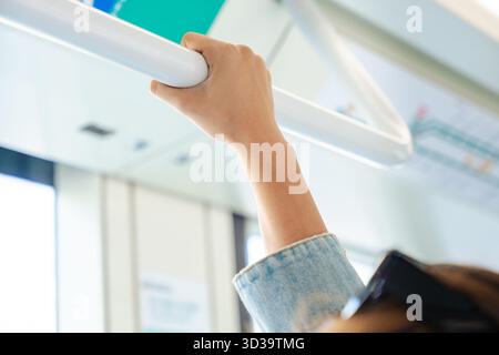Gros plan de la main de femme tenant le rail à l'intérieur des transports publics modernes. Banque D'Images