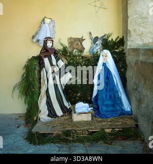 La scène de la Nativité comprend Joseph, Marie, bébé Jésus, un ange, un boeuf, et un âne. Les figures sont disposées sur de la paille devant le feuillage vert, et serties Banque D'Images