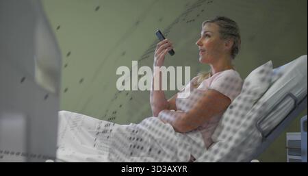 Patient inclinable tenant son smartphone à l'oreille dans le tunnel du scanner de l'hôpital, montrant une feuille blanche Banque D'Images