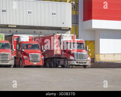 Calgary, Alberta, Canada. 10 avril 2025. Plusieurs camions de livraison Coca-Cola rouges sont stationnés en rangée sur les quais de chargement Banque D'Images