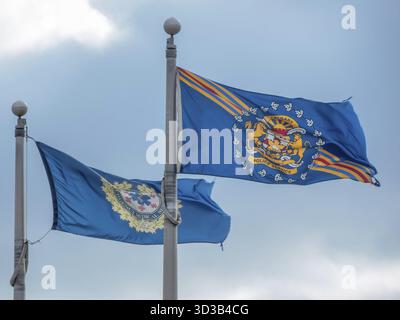 Calgary, Alberta, Canada. 12 mars 2025. Deux drapeaux bleus agitant au vent sur des mâts de drapeau. L'un représente le Service de police de Calgary, et l'autre est fo Banque D'Images