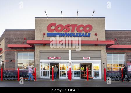 Calgary, Alberta, Canada. 10 mars 2025. Entrée de vente en gros Costco avec acheteurs, chariots et signalisation. Le bâtiment comporte de la brique et du béton avec Lar Banque D'Images