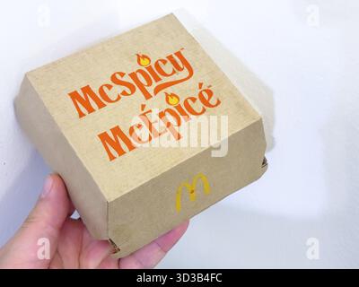 Calgary, Alberta, Canada. 13 mars 2025. Une main tient une boîte de hamburgers McDonald's McSpicy, avec le nom du produit en orange avec des icônes de flamme et le Banque D'Images