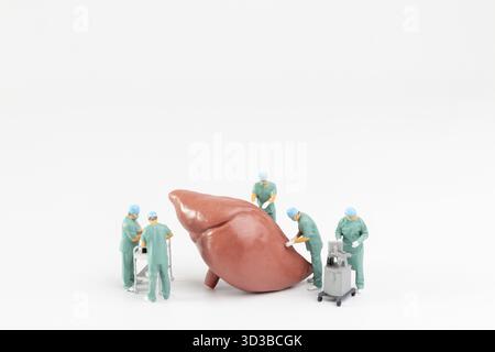 Les personnes miniatures, le médecin et l'équipe médicale d'infirmière effectuent une opération chirurgicale à la salle d'urgence sur fond blanc Banque D'Images