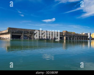 St Nazaire, France - 01 octobre 2025 : bunker massif de U-boat en béton reflété dans le port de Saint-Nazaire, France, sous un ciel bleu vif. Site historique de la seconde Guerre mondiale et point de repère en bord de mer. Banque D'Images
