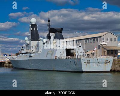 Plymouth, Royaume-Uni - septembre 25 2025 : destroyer D37 de la Royal Navy type 45 amarré au quai de Plymouth, Royaume-Uni, sous des nuages spectaculaires. Navire de guerre moderne avec radars et le White Ensign visible. Banque D'Images