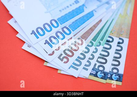 Les billets d'argent gagné sud-coréen en grande quantité se trouvent sur la table de couleur rouge de gros plan. Concept financier et bancaire Banque D'Images