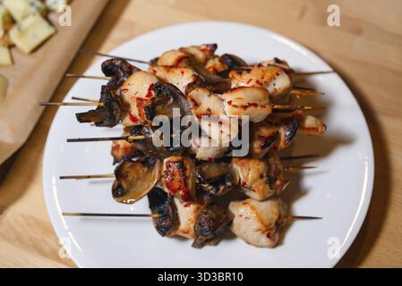 Nourriture, brochettes de poulet grillé juteux et de champignons servies sur une assiette blanche, parfait pour un délicieux apéritif ou un plat principal Banque D'Images