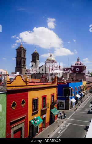 Vue panoramique surélevée du centre-ville historique de Puebla avec des maisons coloniales animées au premier plan et les tours de la cathédrale sous un ciel bleu. Banque D'Images