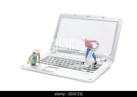 Les personnes miniatures nettoyant l'ordinateur portable par l'eau sur fond blanc Banque D'Images