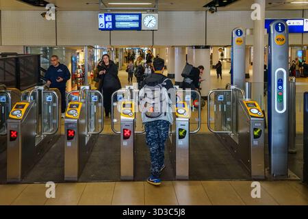 Les passagers avec des bagages passent par les portes d'entrée de la gare centrale d'Amsterdam. Banque D'Images
