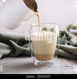 Nourriture, verser un café avec du lait de la théière à la tasse en verre Banque D'Images
