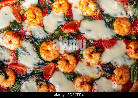 Pizza aux crevettes, tomates et épinards, gros plan. Fond méditerranéen de texture de pizza. Photo de haute qualité Banque D'Images