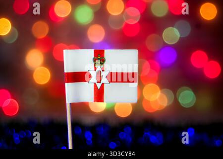 Drapeau d'Irlande du Nord contre le bokeh coloré. Idéal pour la fierté nationale, les célébrations, le tourisme au Royaume-Uni, et les événements associés à la fête de Patrick. Banque D'Images