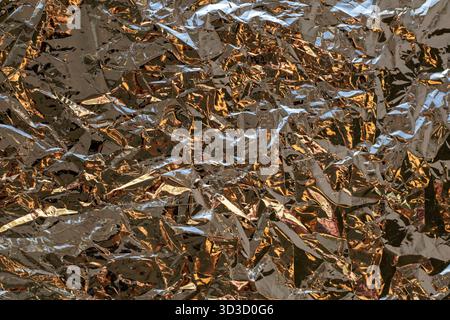Texture de feuille métallique froissée avec des reflets de cuivre et d'argent pour un fond abstrait Banque D'Images