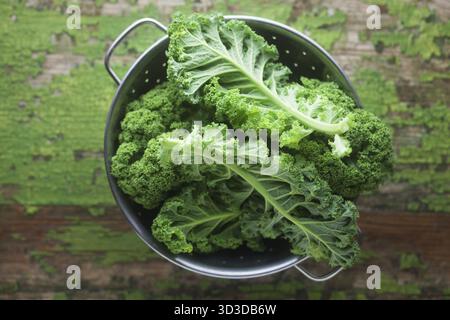 Le borécole cru dans un tamis sur un fond de bois vert Banque D'Images