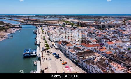 Aérien, Tavira, Portugal lumineux front de mer promenade animée, côte ensoleillée avec des parasols et des bateaux en mouvement, vives vue côtière Banque D'Images