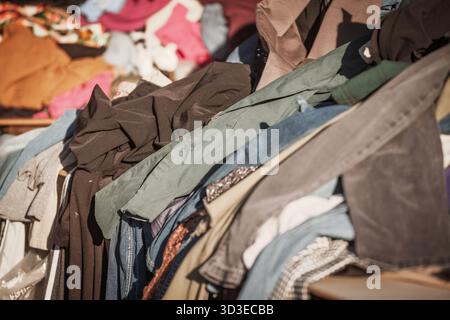 Focus sélectif sur un tas de vêtements de seconde main dans un marché aux puces à Sabac, Serbie. Les tissus mélangés véhiculent la réutilisation, l'épargne et la mode circulaire Banque D'Images