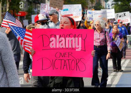 Une femme brandit un panneau "démocratie sur les dictateurs" lors d'une manifestation contre l'administration Trump, le 18 octobre 2025, New York Banque D'Images