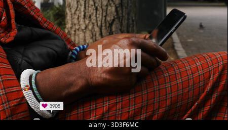 Homme défilant portant un pantalon à carreaux à côté du tronc d'arbre, avec une superposition d'icône de coeur sur le téléphone et les bracelets Banque D'Images