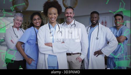 Équipe debout dans la salle de la clinique avec des gommages et des manteaux, stéthoscopes, graphiques, lumières et superpositions vertes Banque D'Images