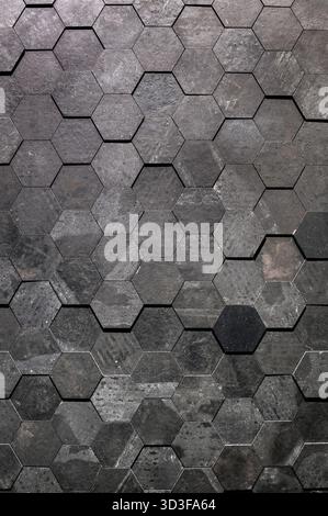 Carreaux hexagonaux gris foncé formant une surface murale texturée géométrique Banque D'Images