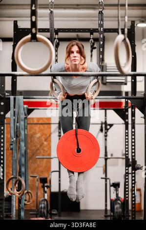 Forte femme de fitness entraînant des muscles avec une plaque de poids dans un gymnase moderne Banque D'Images