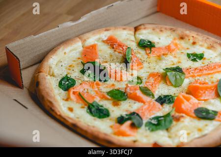 Pizza avec saumon et épinards dans une boîte Banque D'Images
