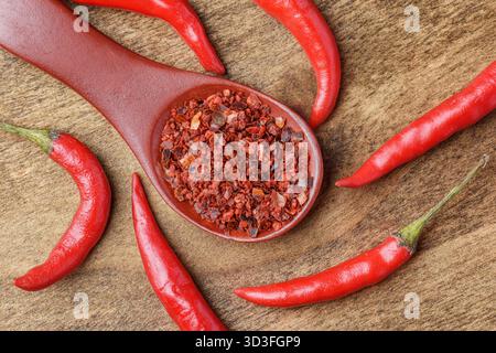 Cuillère en bois de flocons de piment séchés parmi les poivrons frais Banque D'Images
