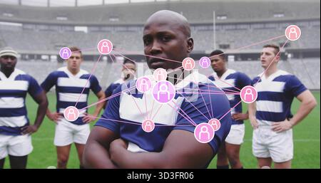 Joueur de rugby debout en maillot rayé croisant les bras sur le terrain en herbe au stade, avec des icônes de nœud Banque D'Images