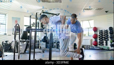 Faire plongeon client penché en avant sur les barres plongeantes dans le gymnase, entraîneur soutenant la cheville portant un équipement de gymnastique Banque D'Images