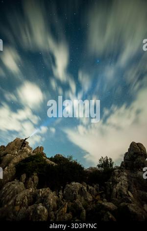 Une superbe photographie nocturne capturant le paysage accidenté de Torcal de Antequera sous un ciel étoilé. Le mouvement dans les nuages ajoute un con dynamique Banque D'Images
