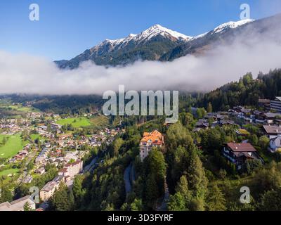 Vue aérienne idyllique sur les Alpes européennes, mettant en valeur un paisible village de montagne niché dans un écrin de verdure et entouré de sommets majestueux, avec un vei Banque D'Images