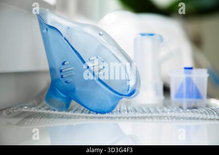Nébuliseur médical avec masque bleu, tubulure et accessoires placés sur un rebord de fenêtre. Concept de soins à domicile, inhalothérapie et traitement respiratoire Banque D'Images