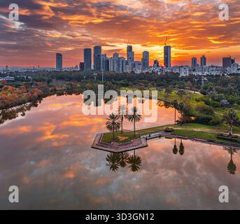 Vue aérienne du coucher de soleil vibrant se reflétant sur les eaux tranquilles du parc Hayarkon, contrastant avec la ligne d'horizon moderne, tel Aviv-Yafo, tel Aviv dis Banque D'Images