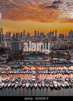 Vue aérienne des yachts nichés dans la marina avec pour toile de fond l'horizon de tel Aviv, baigné dans les teintes chaudes du soleil couchant, tel Aviv-Yafo, Tél Banque D'Images