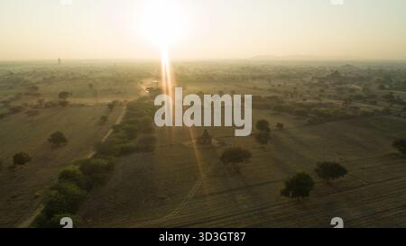 Vue aérienne des temples anciens perçant à travers la brume dorée au lever du soleil, projetant de longues ombres sur les plaines de Bagan, Old Bagan, Mandalay Region, My Banque D'Images